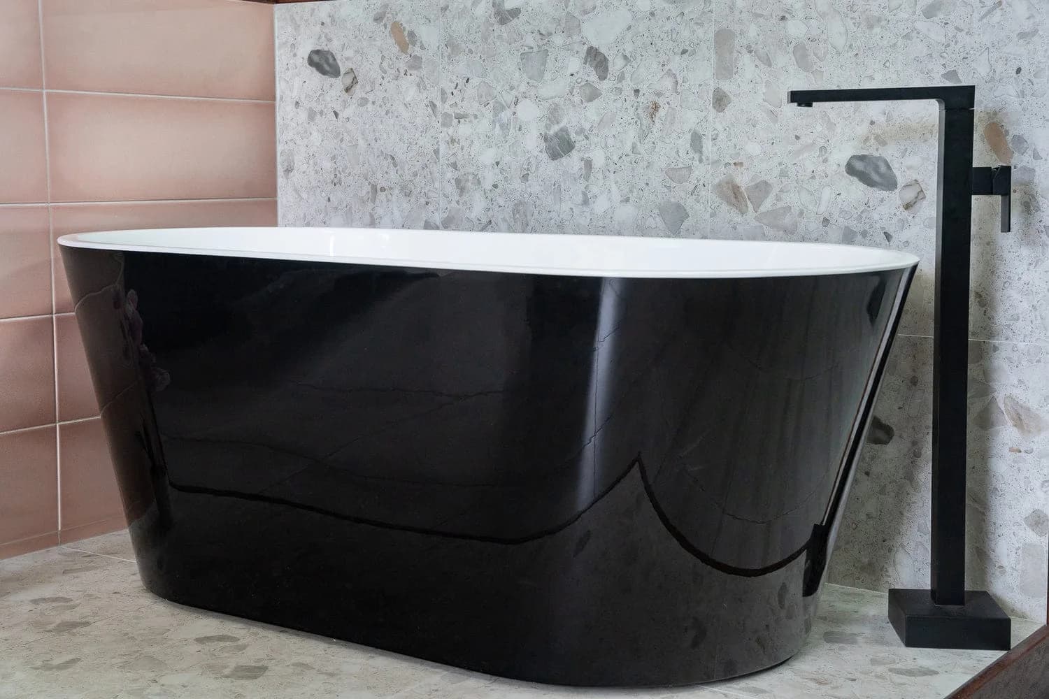 Black freestanding bath in a tiled bathroom